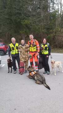 Trije udeleženci akcije skupaj z reševalnimi psi. Reševalci pomagajo ponesrečeni osebi